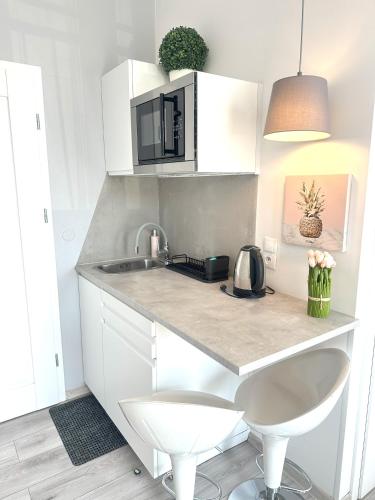 a white kitchen with a sink and a microwave at Exclusive Apartments Smolna in Warsaw
