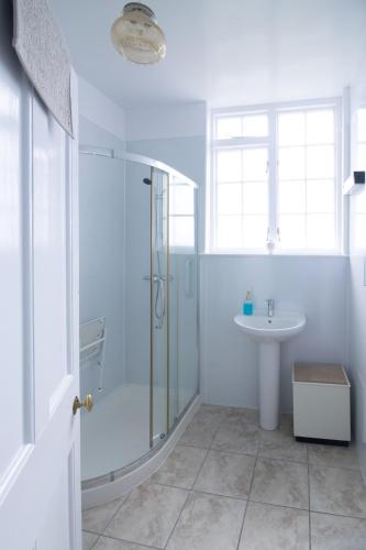 a white bathroom with a shower and a sink at Whatton Cottage in Gullane