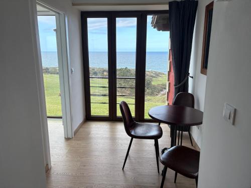 a room with a table and chairs and a view of the ocean at Posada Punta Liñera in San Vicente de la Barquera