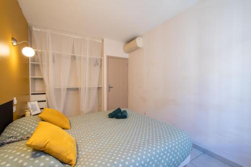 a bedroom with a bed with yellow pillows at Le Faubourg National Climatisé Parking gratuit Wifi in Aigues-Mortes