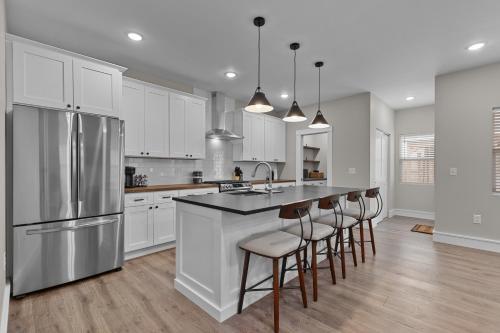 a kitchen with white cabinets and a kitchen island with bar stools at 3325 Bright Urban Comfort in Tower Grove