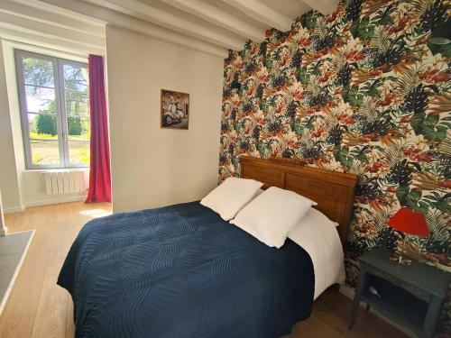 una camera con un letto blu e carta da parati floreale di Les Jardins de l'Orangerie a Durtal
