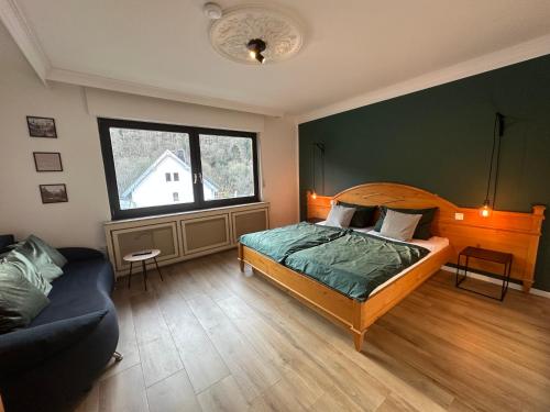a bedroom with a bed and a couch and a window at Gästehaus Heimatliebe in Heimbach