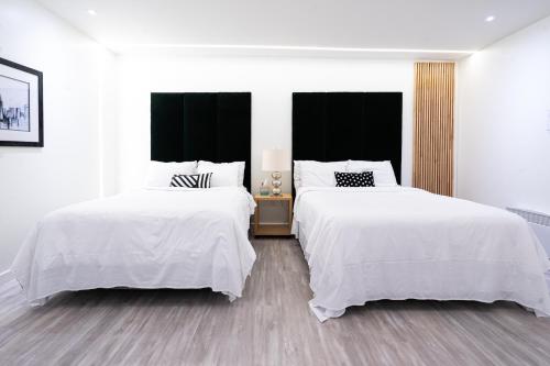 two beds in a bedroom with white walls and wood floors at Modern Loft with Park Like Setting View in Kirkland