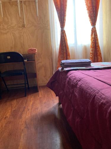 a bedroom with a bed with a purple blanket and a window at Ecosenderos in Puerto Cisnes