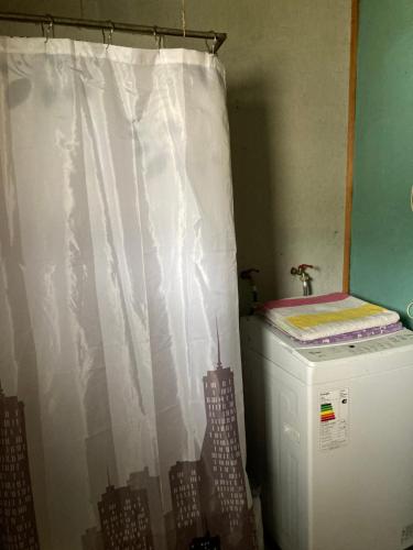 a white shower curtain in a room with a refrigerator at Ecosenderos in Puerto Cisnes