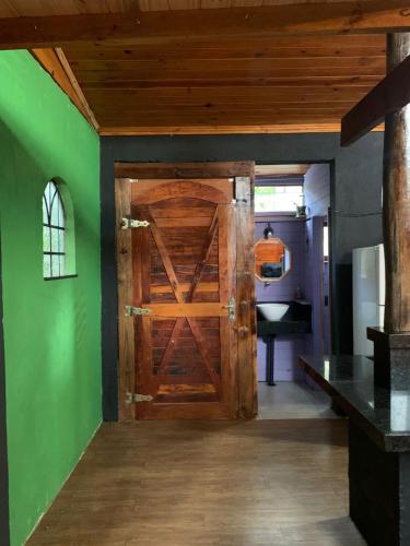 a wooden door in a room with a green wall at Cabana Urbana in Cascavel