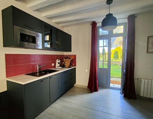 d'une cuisine avec des placards noirs, un évier et une fenêtre. dans l'établissement Les Jardins de l'Orangerie, à Durtal