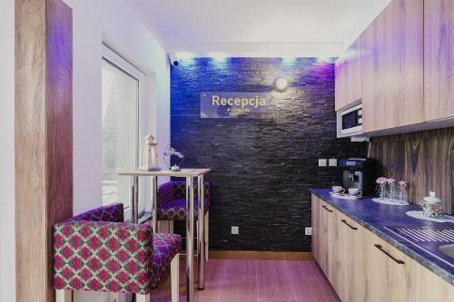 a kitchen with purple chairs and a black brick wall at PIONOW Pokoje WaWa - adults only in Krynica Morska