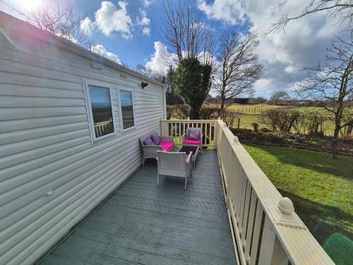 a deck with chairs and tables on a house at 24 The Beeches Caravan Park in Gilcrux