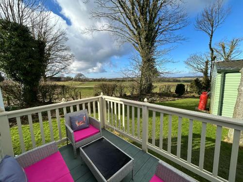 a deck with a bench and a chair on a fence at 24 The Beeches Caravan Park in Gilcrux