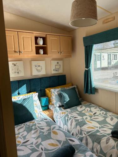 a small room with two beds and a window at 24 The Beeches Caravan Park in Gilcrux