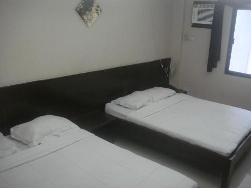 two beds in a small room with two white pillows at Hidden Pearl Hotel (Janus Luxury Suites) in Angeles