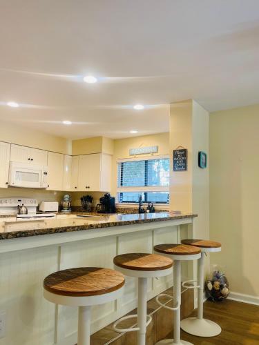 a kitchen with three stools at a counter at 13 Beach Stop Hilton Head in Hilton Head Island