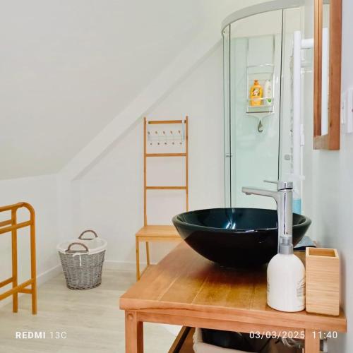 une salle de bain avec un lavabo noir sur une table en bois dans l'établissement Charmant cocon breton proche plage, GR34, parking, à Pordic