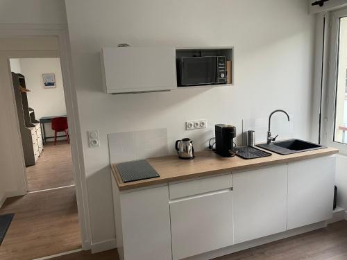 une cuisine avec des armoires blanches et un micro-ondes dans l'établissement Appartement T2 - 202 - Hyper Centre - Intégralement rénové - Toutes commodités à pied, à Saint-Nazaire