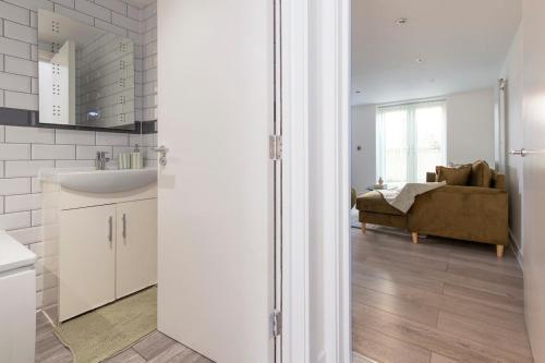 a bathroom with a sink and a living room with a couch at The Green Haven-Cozy luxury flat in Crayford in Slades Green