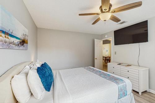 a bedroom with a white bed and a ceiling fan at The MOasis in Panama City Beach