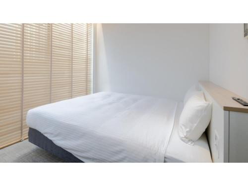 sypialnia z białym łóżkiem i oknem w obiekcie The OneFive Sendai - Vacation STAY 35224v w mieście Sendai