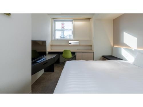 a bedroom with a bed and a desk and a window at The OneFive Sendai - Vacation STAY 35252v in Sendai