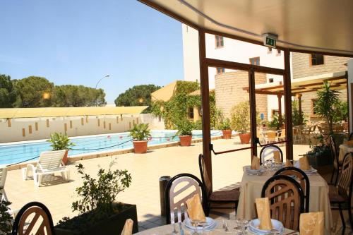 a patio with tables and chairs next to a pool at Hotel Tre Torri in Villaggio Mosè