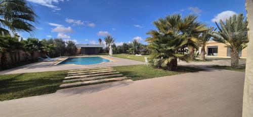 a backyard with a swimming pool and palm trees at Villa Al Firdaous in Tiznit