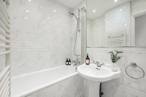 a white bathroom with a sink and a bath tub at 2 Bedr, 3 Beds, 1 Bath Thames, Trafalgar SQ in London