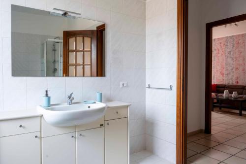 a white bathroom with a sink and a mirror at Casa vacanza Nada in Dogliani