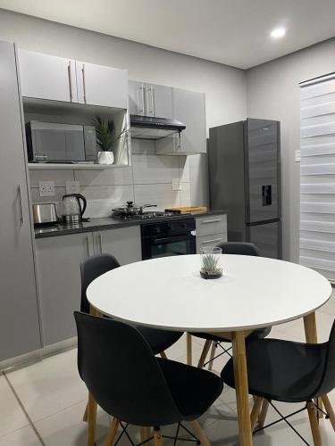 a kitchen with a white table and chairs in it at iThusi-CBD in Mbabane