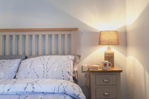 a bedroom with a bed and a lamp on a night stand at Cosy Cottage in the Heart of Charnwood Forest in Woodhouse
