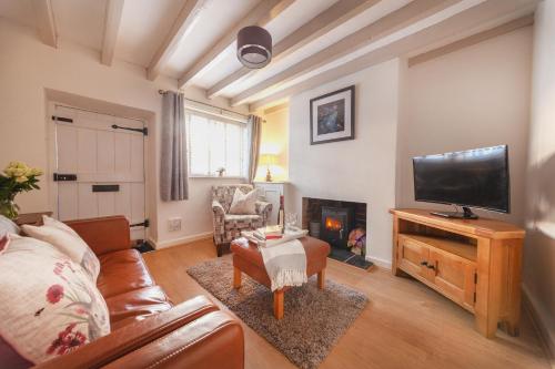 a living room with a couch and a tv and a fireplace at Cosy Cottage in the Heart of Charnwood Forest in Woodhouse
