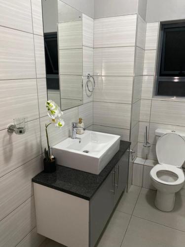 a white bathroom with a sink and a toilet at iThusi-CBD in Mbabane
