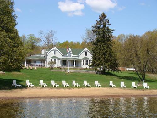 a group of chairs sitting on the beach in front of a house at Port Cunnington Lodge in Dwight
