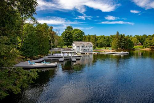 a house on the water with boats on a dock at Port Cunnington Lodge in Dwight