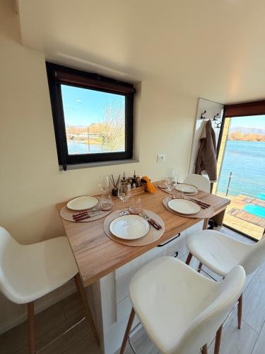 a wooden table with white chairs and a large window at 446 Tiny House Zues in Shkodër