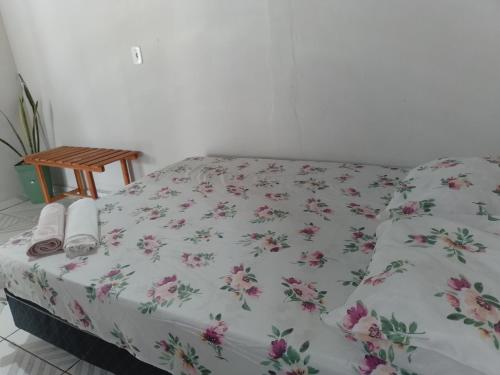 a bed with a floral bedspread with towels on it at Pousada Recanto do Mar in Tutóia