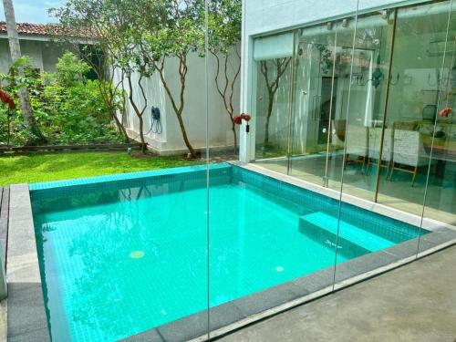 a swimming pool in a house with glass walls at Sanctuary Ceylon by Ceylon Spaces in Mount Lavinia