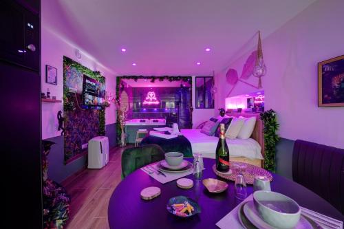 - une chambre violette avec un lit et une table avec une bouteille de vin dans l'établissement L'Inséparable - Jacuzzi - Terrasse - Parking - Vélos, à Fondettes