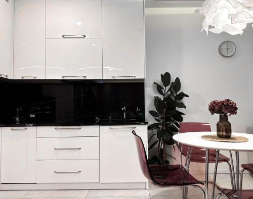 a kitchen with white cabinets and a table at InPoint Central Apartments in Kraków