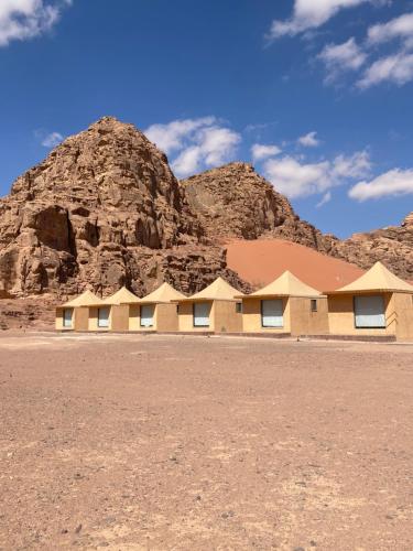 a building in the desert with a mountain in the background at Wadi Rum Santa Camp in Wadi Rum