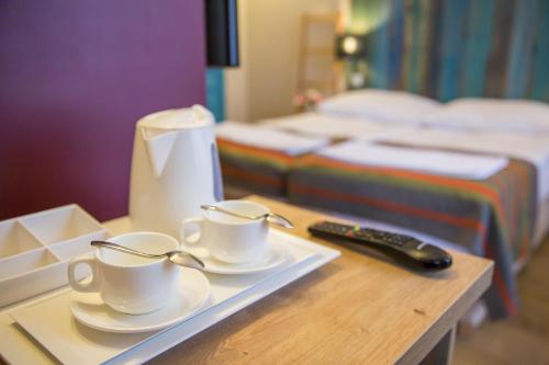 a tray with two coffee cups and a remote control at Willa Sudety in Kudowa-Zdrój