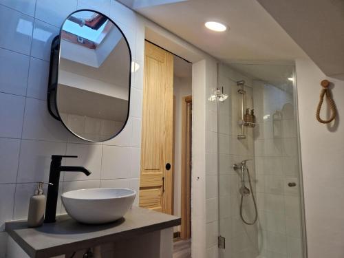 Un baño con lavabo, espejo y ducha. en Casa Cosmeiro, en Sierra de Outes