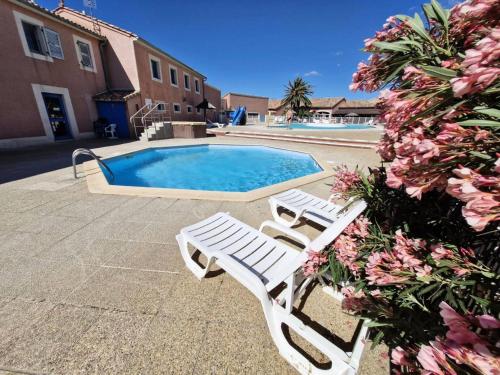 - deux chaises blanches installées à côté de la piscine dans l'établissement Résidence Ile Des Pecheurs - VILLA 3 PIECES 6 couchages LE BARCARES MAE-2001, au Barcarès