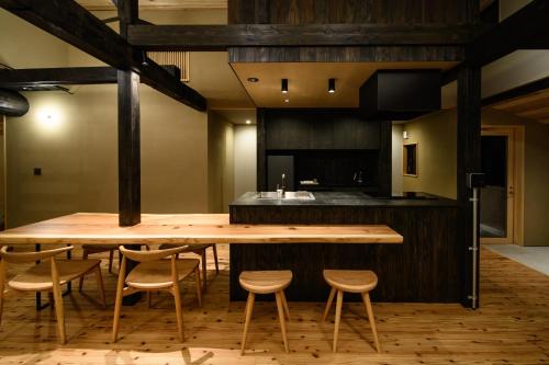 a kitchen with a large wooden table and chairs at JINEN hida takayama in Machikata