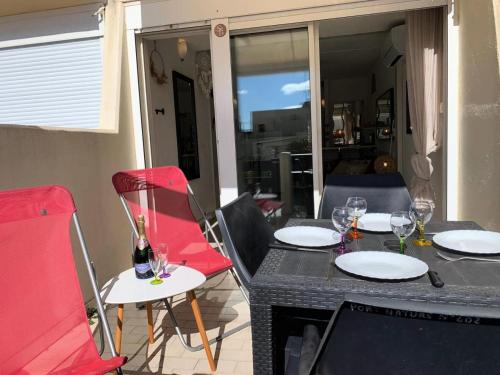 - une table avec des chaises rouges et des verres à vin dans l'établissement Résidence Port Nature Colline 4 - Studio 2 PERS - Port Nature Colline 4 rez-de-jardin MAE-6174, au Cap d'Agde