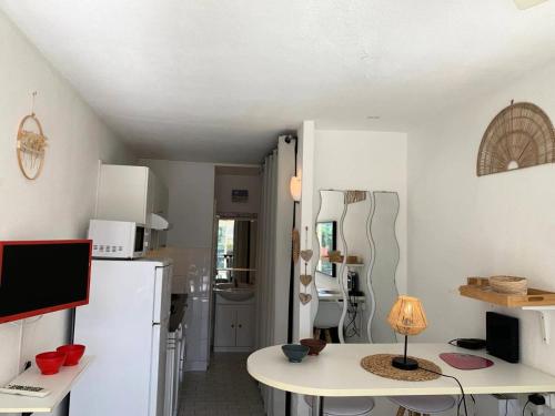 Il comprend une cuisine équipée d'un réfrigérateur blanc et d'une table avec une lampe. dans l'établissement Résidence Port Nature Colline 4 - Studio 2 PERS - Port Nature Colline 4 rez-de-jardin MAE-6174, au Cap d'Agde