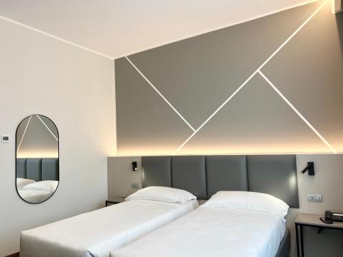 two beds in a room with a mirror at Unico Hotel in Ossona