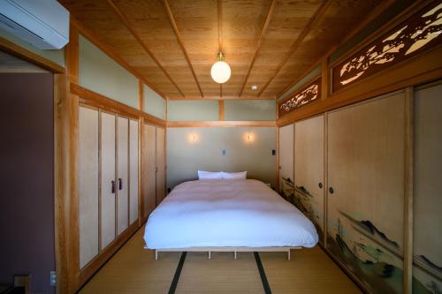 a small bedroom with a white bed in it at JINEN hida takayama in Machikata