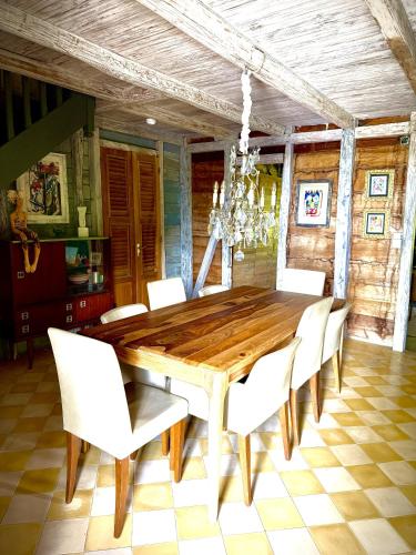 a dining room with a wooden table and white chairs at Habitation Caféière Samana Beauséjour - GUESTHOUSE in Pointe-Noire