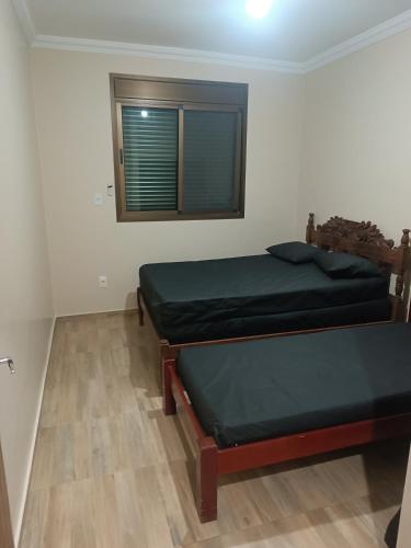 two beds in a room with a window at Casa de campo Serra do Cipó in Serra do Cipo